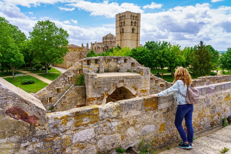 Photo of Woman overlooking the wall contemplating the beauty of the cathedral of Zamora Spain.