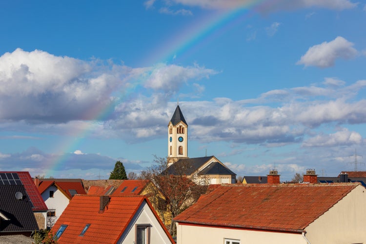 Photo of Christian Church in background of rainbow in Frankenthal Germany.