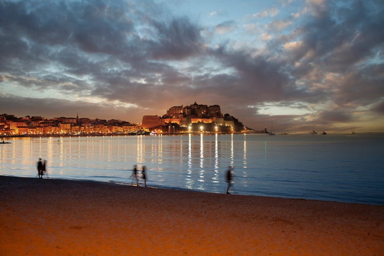 Beach in Calvi Corsica france, at sunset over the bay and with the citadel silhouette.