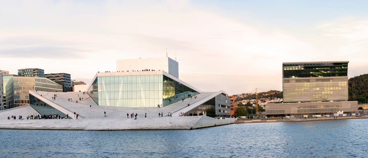 Oslo, Norway. Scenic Night Evening View Of Illuminated Norwegian National Opera And Ballet House Among Contemporary High-Rise Buildings. Panorama, Panoramic View.