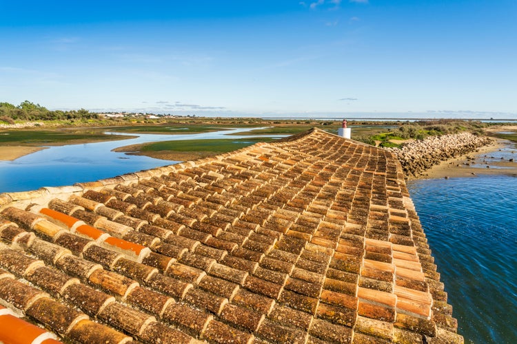 Photo of Beautiful landscape of Ria Formosa Natural Park with a tiled roof in the foreground, Olhao, Algarve, Portugal.