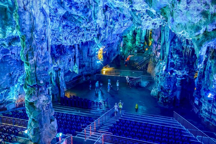 A cave interior in Gibraltar is illuminated by blue lighting, showcasing unique rock formations and a serene atmosphere..png