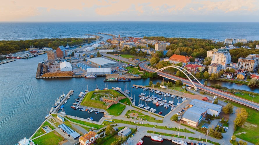 A breathtaking aerial drone photo of Kołobrzeg's marina in Poland captures a picturesque scene. The view showcases a multitude of yachts, sailboats, fishing boats and ships.