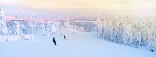 Photo of stunning sunset view over wooden huts and snow covered trees in Kuusamo, Finnish Lapland.