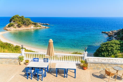 Photo of tables with chairs on a terrace with view of beautiful Kokkari bay, Samos island, Greece.