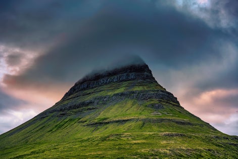 photo of Close up of Moody Kirkjufell mountain peak with cap cloud covered in the sunset on summer at Iceland