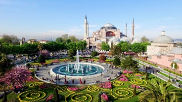 Touristic sightseeing ships in Golden Horn bay of Istanbul and mosque with Sultanahmet district against blue sky and clouds. Istanbul, Turkey during sunny summer day.