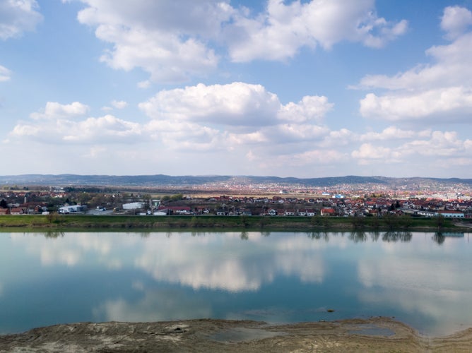 photo of Scenic view of Sava river and settlements around Slavonski Brod during sunny day with fluffy clouds.