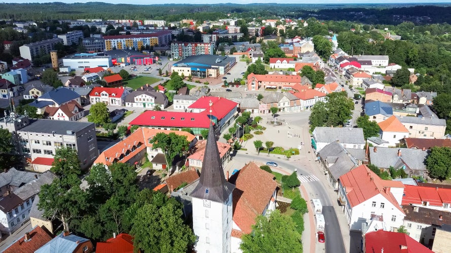 Aerial View of the Holy Trinity Lutheran Church in Tukums, Latvia. Golden Cock Statue on the Top of Tower. Tukums City Park on the the Background. Sunny Summer Day.