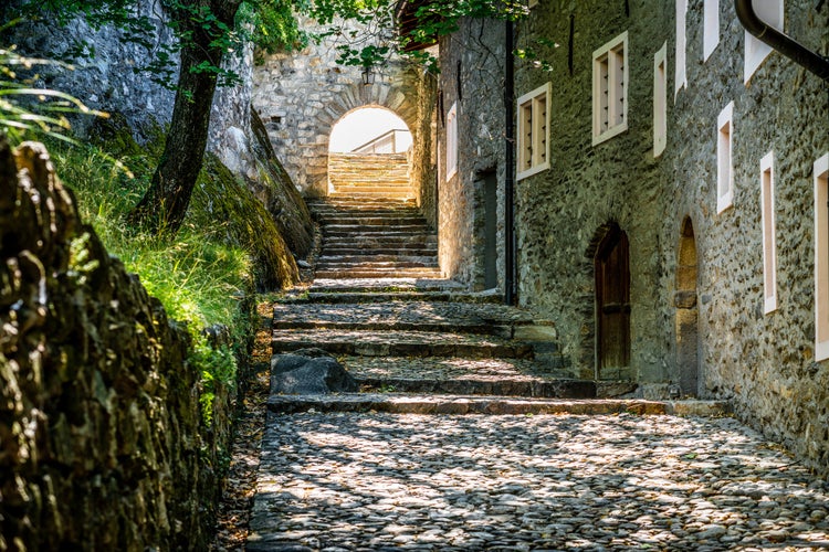 Photo of Pedestrian alley view of the Valere Basilica with old medieval buildings and paved road in Sion Valais Switzerland