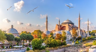 Touristic sightseeing ships in Golden Horn bay of Istanbul and mosque with Sultanahmet district against blue sky and clouds. Istanbul, Turkey during sunny summer day.