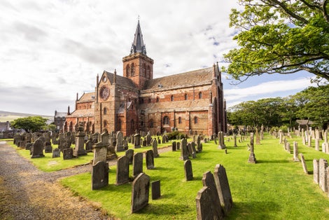 photo of St Magnus Cathedral and surrounding gothic graveyard in Kirkwall, Orkney Islands, Scotland. The holy red sandstone architecture is part of the church of Scotland.