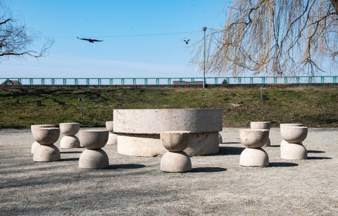 Photo of Stone table and stones - Table of Silence. Crows flying in the blue sky. A walk on a spring day through the park in Targu Jiu.