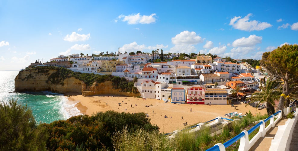 Photo of View of the sandy beach surrounded by typical white houses in a sunny spring day, Carvoeiro, Lagoa, Algarve, Portugal.