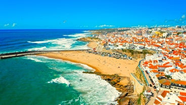 Photo of aerial view over People Crowd Having Fun On Beach And Over Cascais City In Portugal.