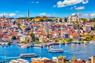 Touristic sightseeing ships in Golden Horn bay of Istanbul and mosque with Sultanahmet district against blue sky and clouds. Istanbul, Turkey during sunny summer day.