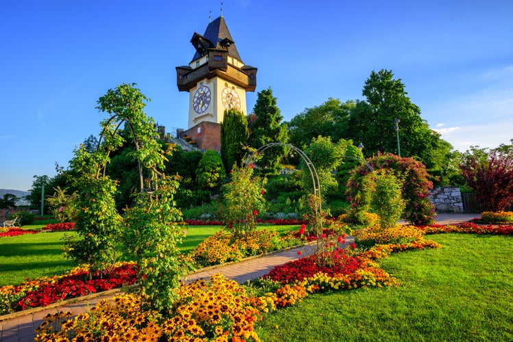 Photo of the medieval Clock tower Uhrturm in flower garden on Shlossberg hill, Graz, Austria.