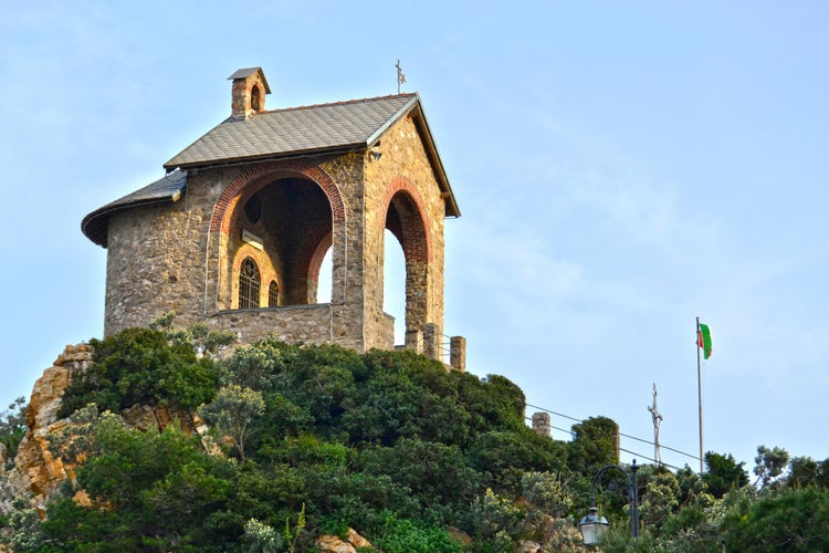 Photo of small church located on a hill at the entrance to the port of Alassio, Liguria, Italy.