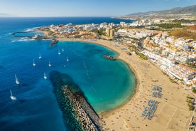 photo of aerial shot of Costa Adeje area, South Tenerife, Spain. Captured at golden hour, warm and vivid sunset colors. Luxury hotels, villas and restaurants behind the beach.