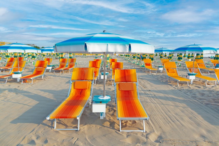 Photo of Blue umbrellas and chaise lounges on the beach of Rimini in Italy.