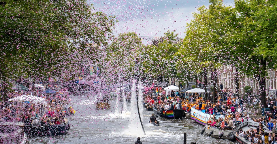 Crowds celebrating along Amsterdam’s canals during a Pride parade with confetti in the air..jpg