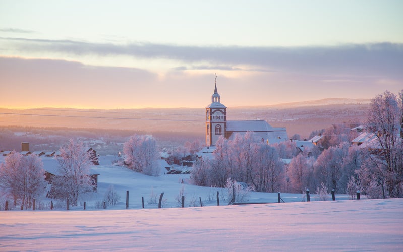 photo of view of Beautiful sunset at the small Norwegian town Roros. Church in the evening sun. Scandinavian winter landscape.