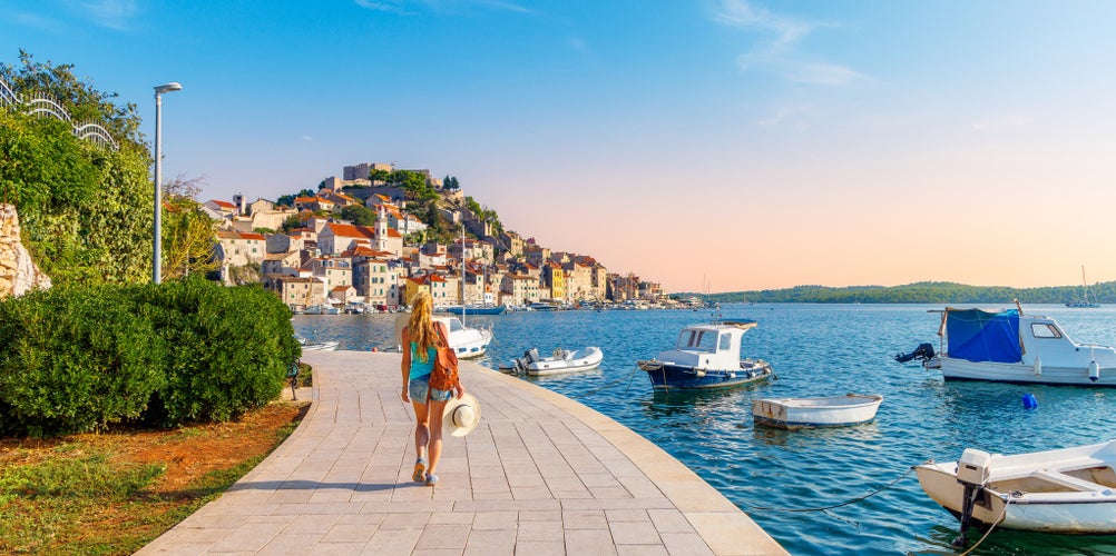 one person walking along the sea with boats, town of Sibenik- travel, tourism in Croatia- Europa