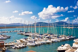 Photo of aerial view of Alghero on a beautiful day with harbor and open sea, Italy.