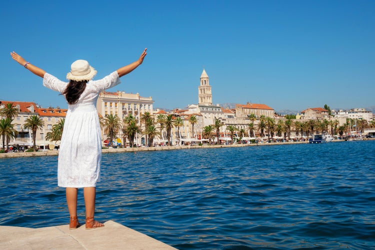 Photo of woman traveler enjoying the view of the beach and old town of Split in Dalmatia, Croatia.