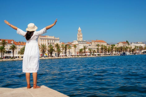 Photo of woman traveler enjoying the view of the beach and old town of Split in Dalmatia, Croatia.