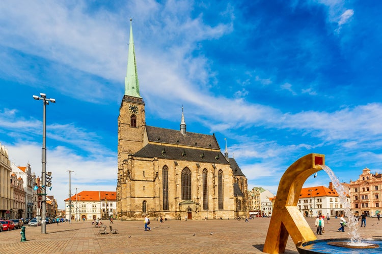 St. Bartholomew's Cathedral in the main square of Plzen with a fountain on the foreground against blue sky and clouds sunny day. Czech Republic, Pilsen. Famous landmark in Czech Republic, Bohemia.