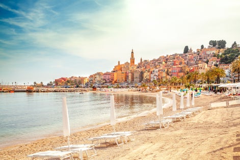 Sunny beach with chairs and umbrellas in Menton, French Riviera, France