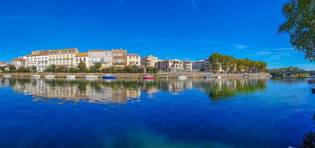 photo of view of Panorama view of Herault river at the town Agde with buildings and boats, Languedoc-Roussillon France.