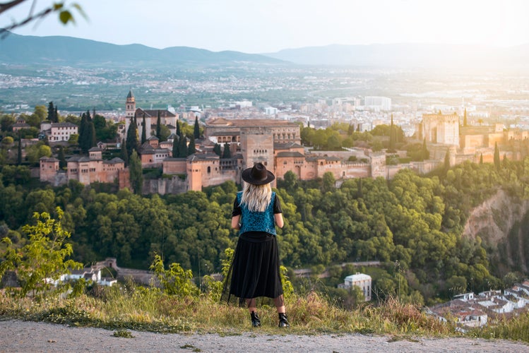 Photo of  young female traveler contemplates the views of the Alhambra palace in the city of Granada, Spain