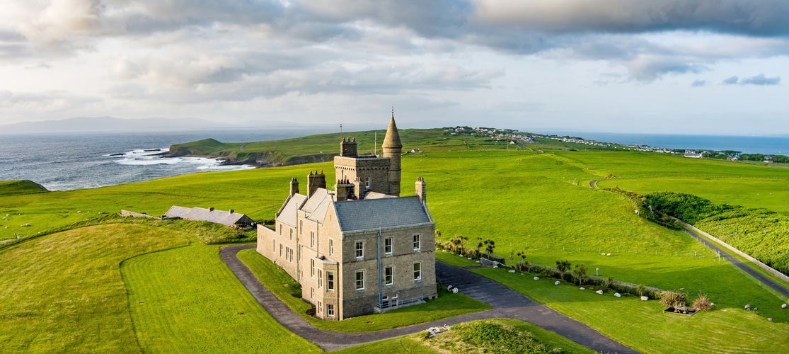 Classiebawn Castle on a backdrop of picturesque landscape of Mullaghmore Head. Spectacular sunset view with huge waves rolling ashore. Signature point of Wild Atlantic Way, Co. Sligo, Ireland