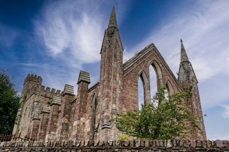 Photo of Front and perspective view of ruins of an old Gothic church in the Irish town of Wexford with blue sky and white clouds.