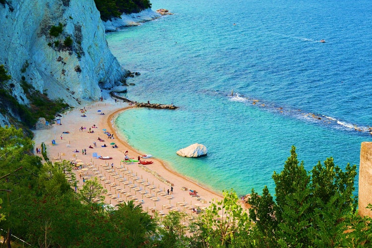 Photo of beautiful beach with sunbeds and umbrellas, Sirolo, Marche, Italy from above.