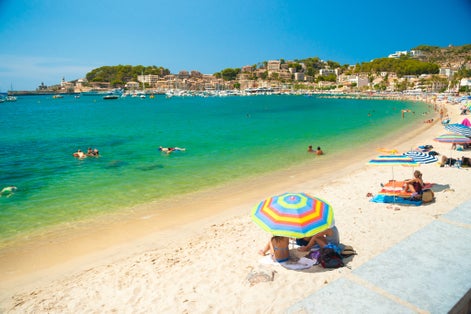 Colorful umbrellas on Puerto de Soller, Port of Mallorca island in balearic islands, Spain. Beautiful picture of people resting on the beach on bright summer day.