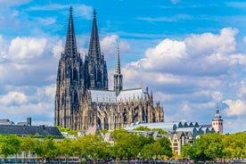 Cologne Aerial view with trains move on a bridge over the Rhine River on which cargo barges and passenger ships ply. Majestic Cologne Cathedral in the background.