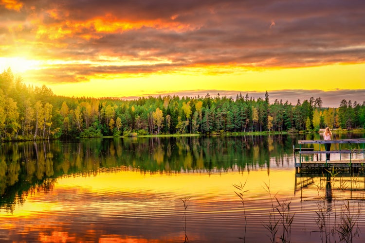 photo of young woman enjoying beautiful sunset at Nossen lake near Vimmerby, Sweden.