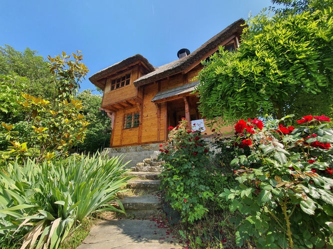 A wooden cabin surrounded by flowers and bushes in a botanical garden in Szeged, Hungary