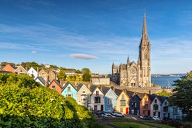 Photo of Colorful row houses with towering cathedral in background in the port town of Cobh, County Cork, Ireland.