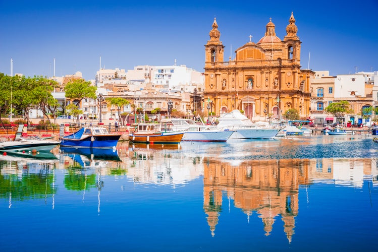 Photo of Marina boat and church reflection into water, Valletta, Malta.