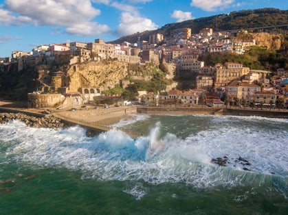 Aerial view of Pizzo Calabro, broken pier, castle, Calabria, tourism Italy. Houses on the rock. On the cliff stands the Murat Aragonese castle. Seafront at sunset. Sea storm and waves with wind