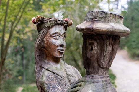 photo of old wooden sculpture in the forest, a man and a woman dancing .Witch hill park, Lithuania.
