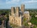 Photo of aerial view of Lincoln cathedral in morning light with stunning towers large medieval architecture west face sitting on hill overlooking historic city.