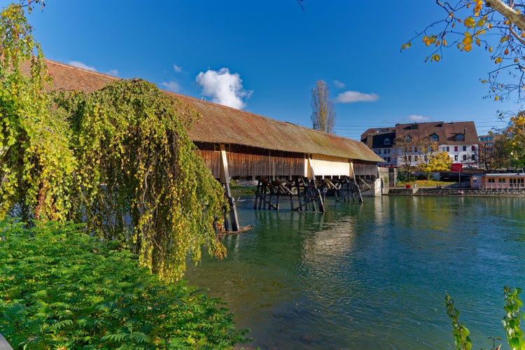 Photo of beautiful covered wooden bridge over Aare River at the old town of Swiss City of Olten on a sunny autumn day, Switzerland.