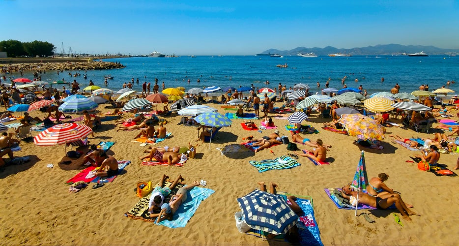 A crowd of vacationers enjoy the warm beaches of Cannes, France during the summer.