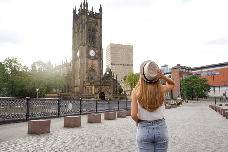 Photo of tourist girl walking in Manchester city on sunny day, England, United Kingdom.