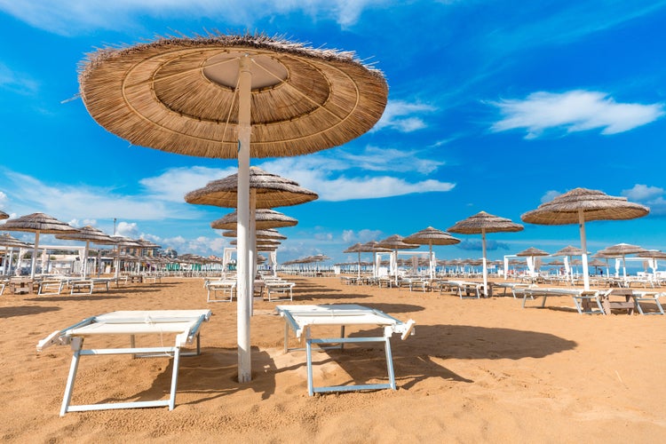 Photo of Umbrellas and chaise lounges on the beautiful beach of Rimini in Italy.